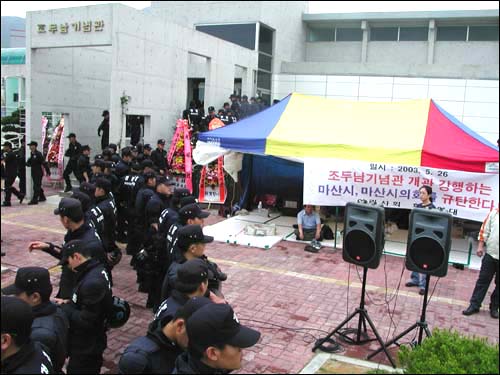 개관식 행사장과 시민단체의 천막농성장을 경찰이 가로질러 막아 서 있는 모습. 